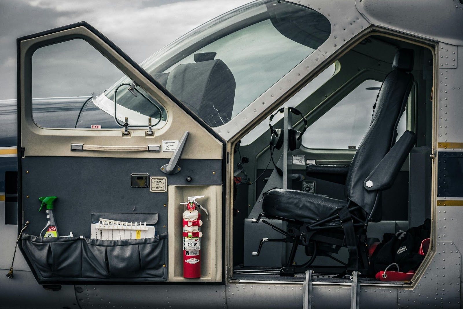 Open cockpitdeur van een klein vliegtuig met de stoel van de piloot, vluchtbesturing en essentiële apparatuur. Dit benadrukt de complexiteit van luchtvaartoperaties en de cruciale rol van het efficiënt aanschaffen van onderdelen en benodigdheden.