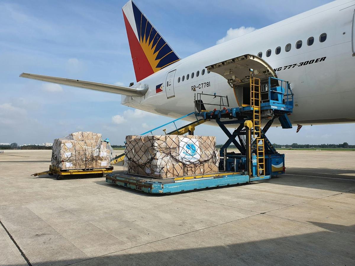 Air cargo logistics in action: a blue sky with clouds with a runway and an airplane being loaded with avionics freight.