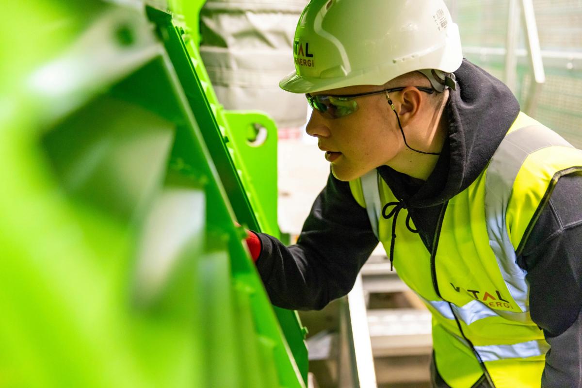 An engineer in safety gear inspects industrial machinery up close, representing the precision and quality control required in FAA-certified PMA parts manufacturing for aviation.