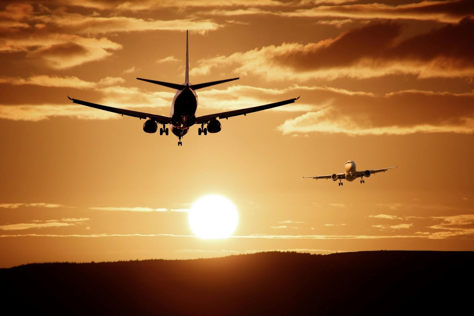 Twee vliegtuigen landen bij zonsondergang in een gedeeld luchtruim. Dit symboliseert de rol van luchtvaartveiligheid en samenwerking, die wordt versterkt door strenge naleving van documentverificatie.