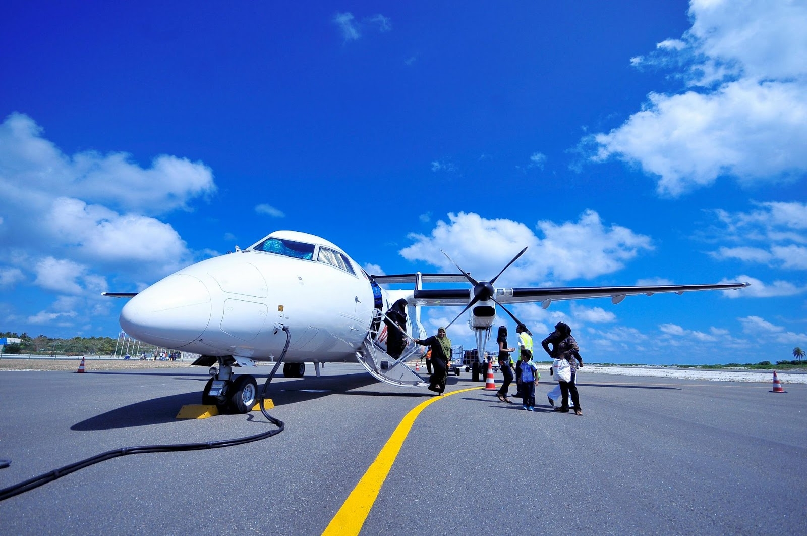 Uma aeronave turboélice regional na pista, passando por modificações ou inspeções, enquanto os passageiros embarcam.