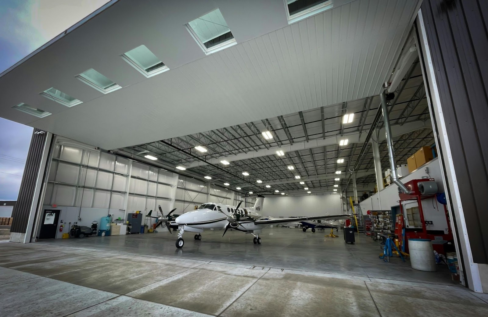 Aircraft inside a well-lit aviation maintenance hangar with open doors, showcasing a modern facility used for fleet management and repairs. The image highlights the role of ERP analytics in optimizing maintenance schedules and operational efficiency.