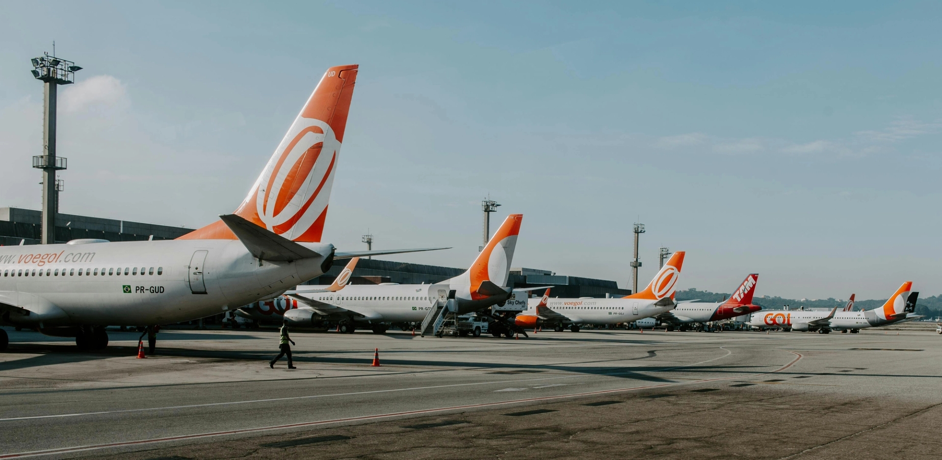 Várias aeronaves Boeing 737 da GOL Airlines alinhadas no portão de um aeroporto, enfatizando a estratégia de frota padronizada da companhia aérea.