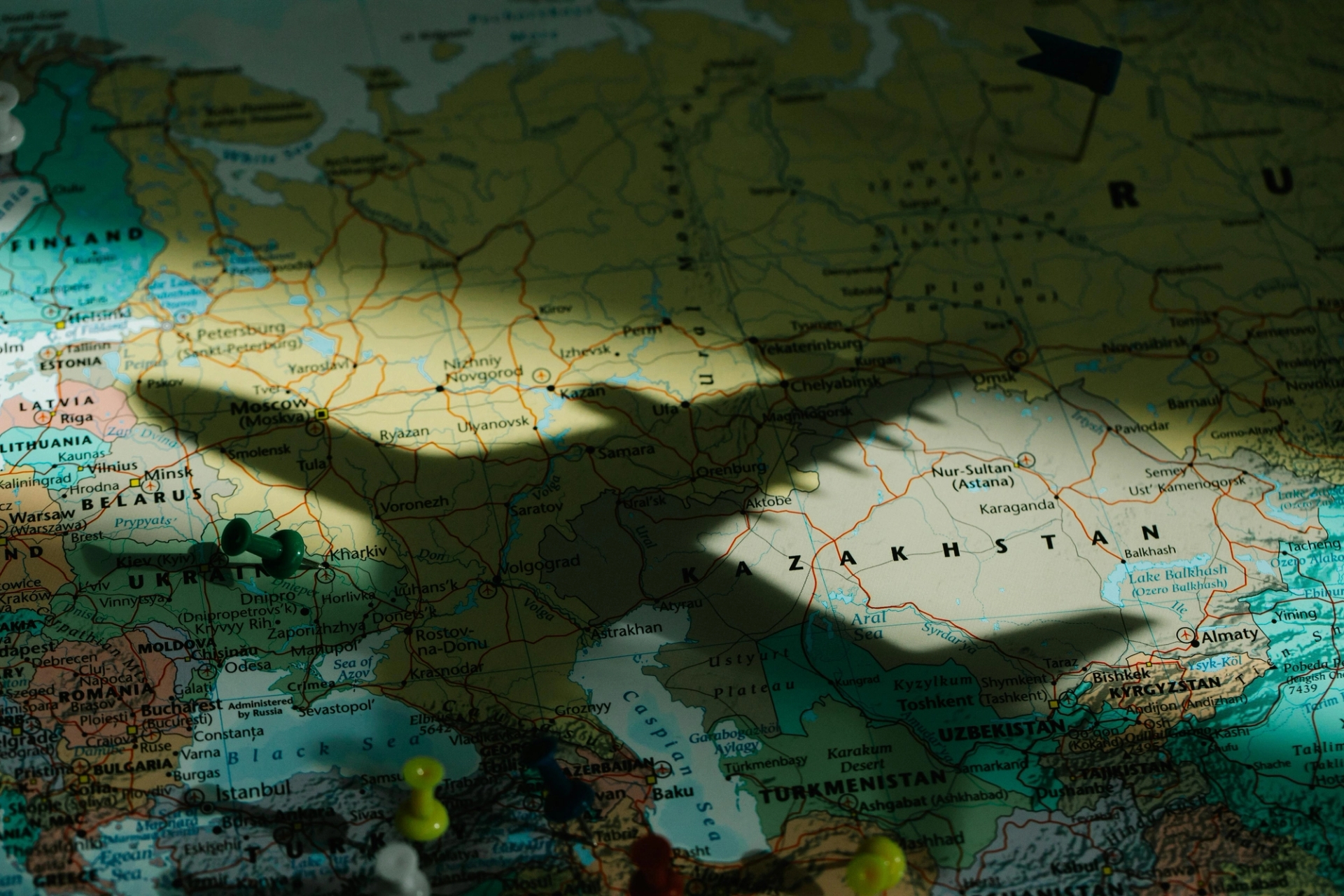 Photo of a model plane shadow over a global map with pins stuck in different hub cities. 
