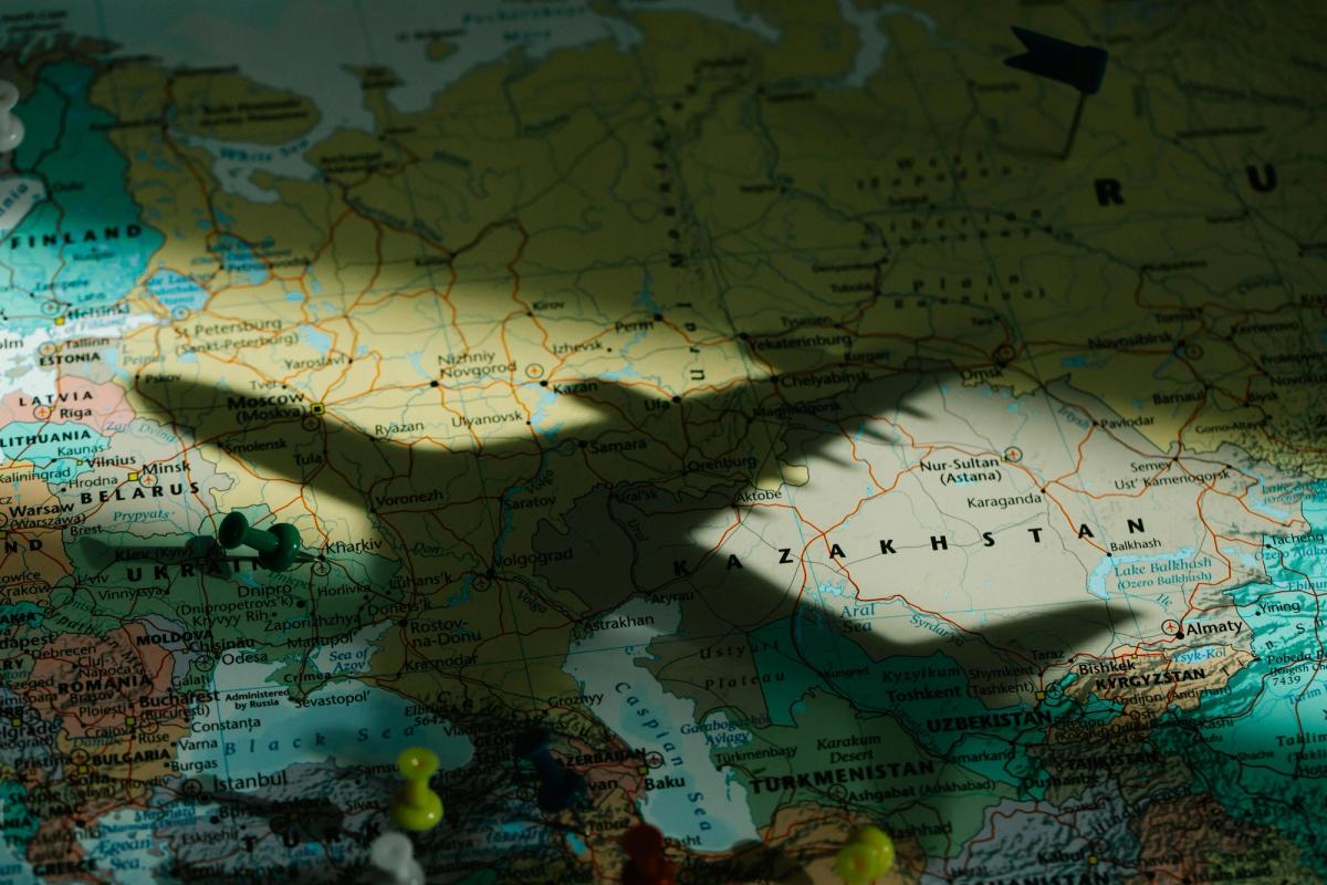 Photo of a model plane shadow over a global map with pins stuck in different hub cities.