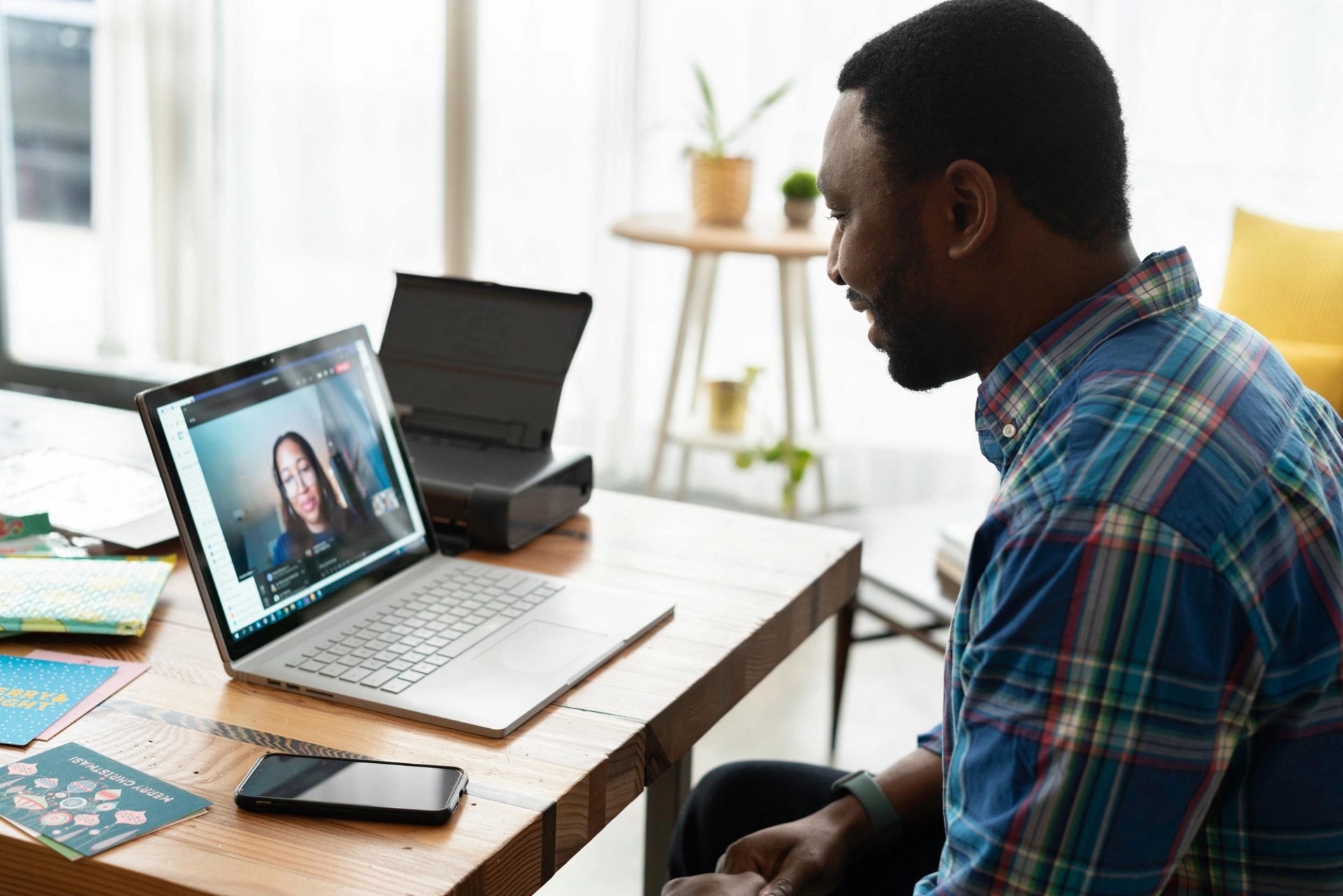 Man seated at laptop at his dining room table is on a sales call over video conference software.