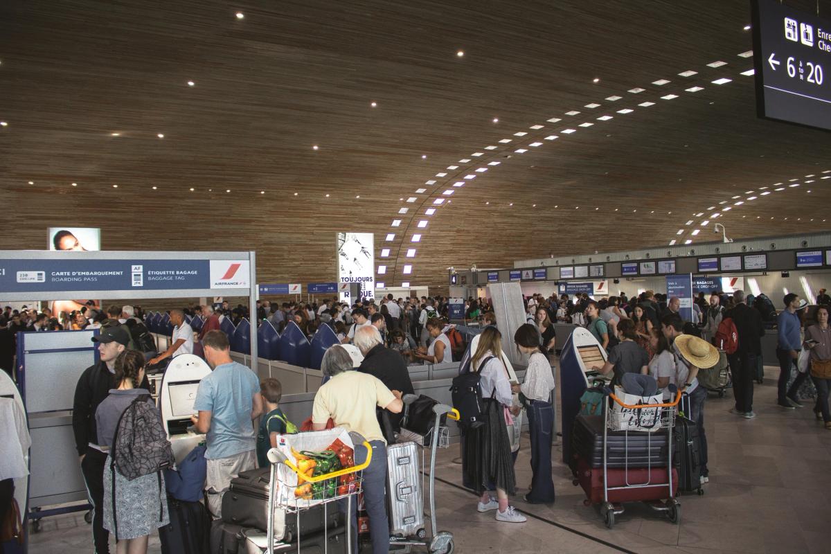 Passengers at a crowded airport are sold personalized retail experiences via check-in kiosks. 