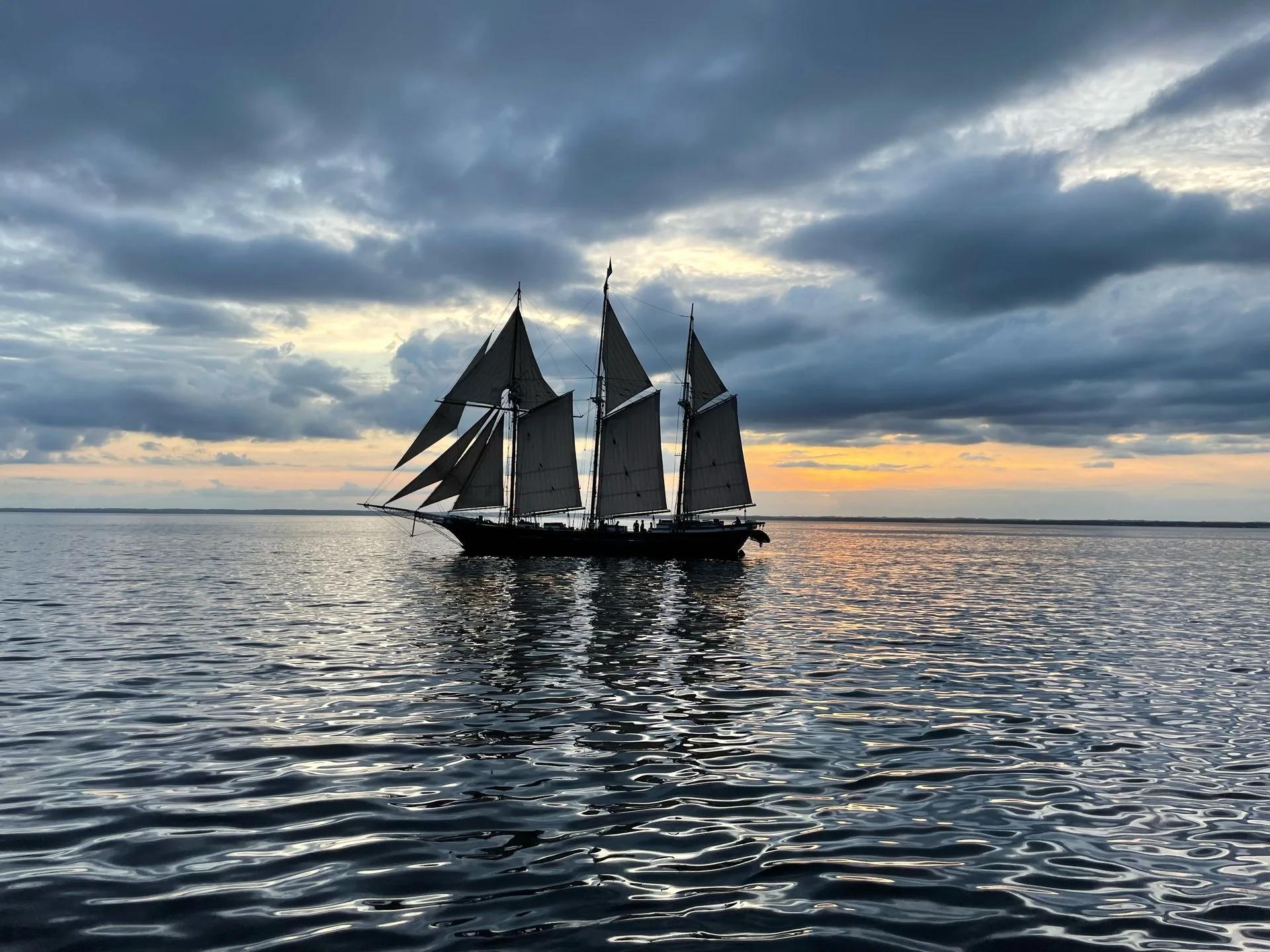 A traditional schooner under sail against the evening sky