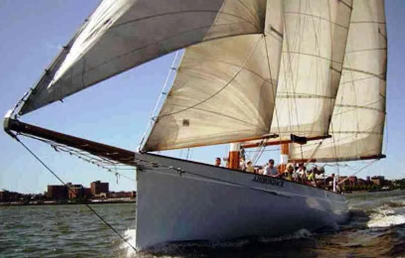 A schooner under full sail with passengers on deck