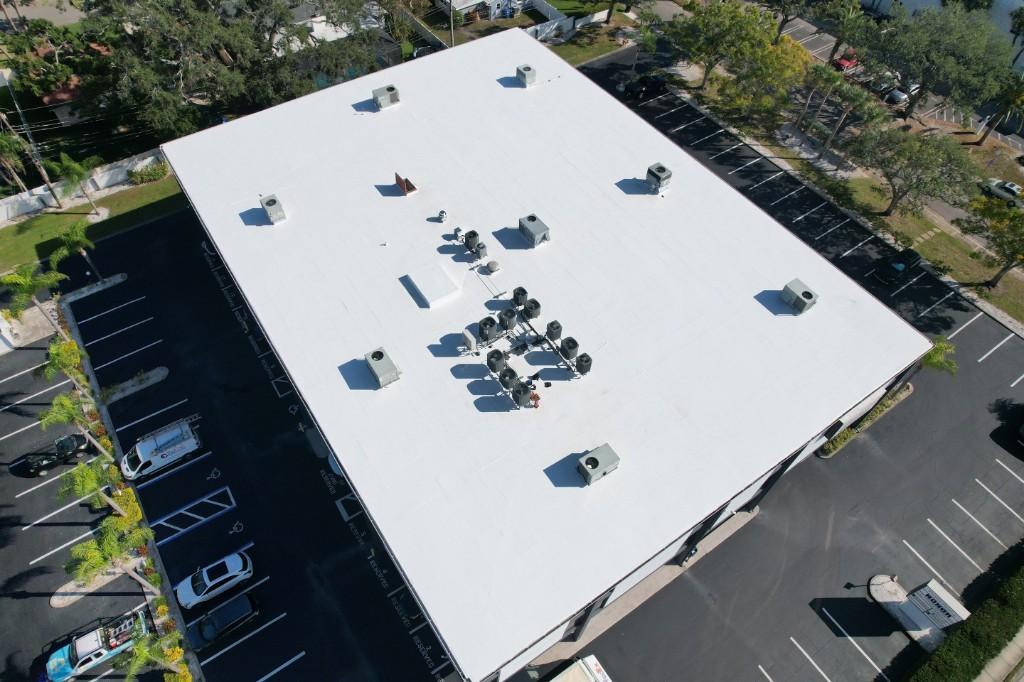 White GAF TPO flat roof with rooftop units on an office building in St. Petersburg, parking lots on both sides, seen from a drone