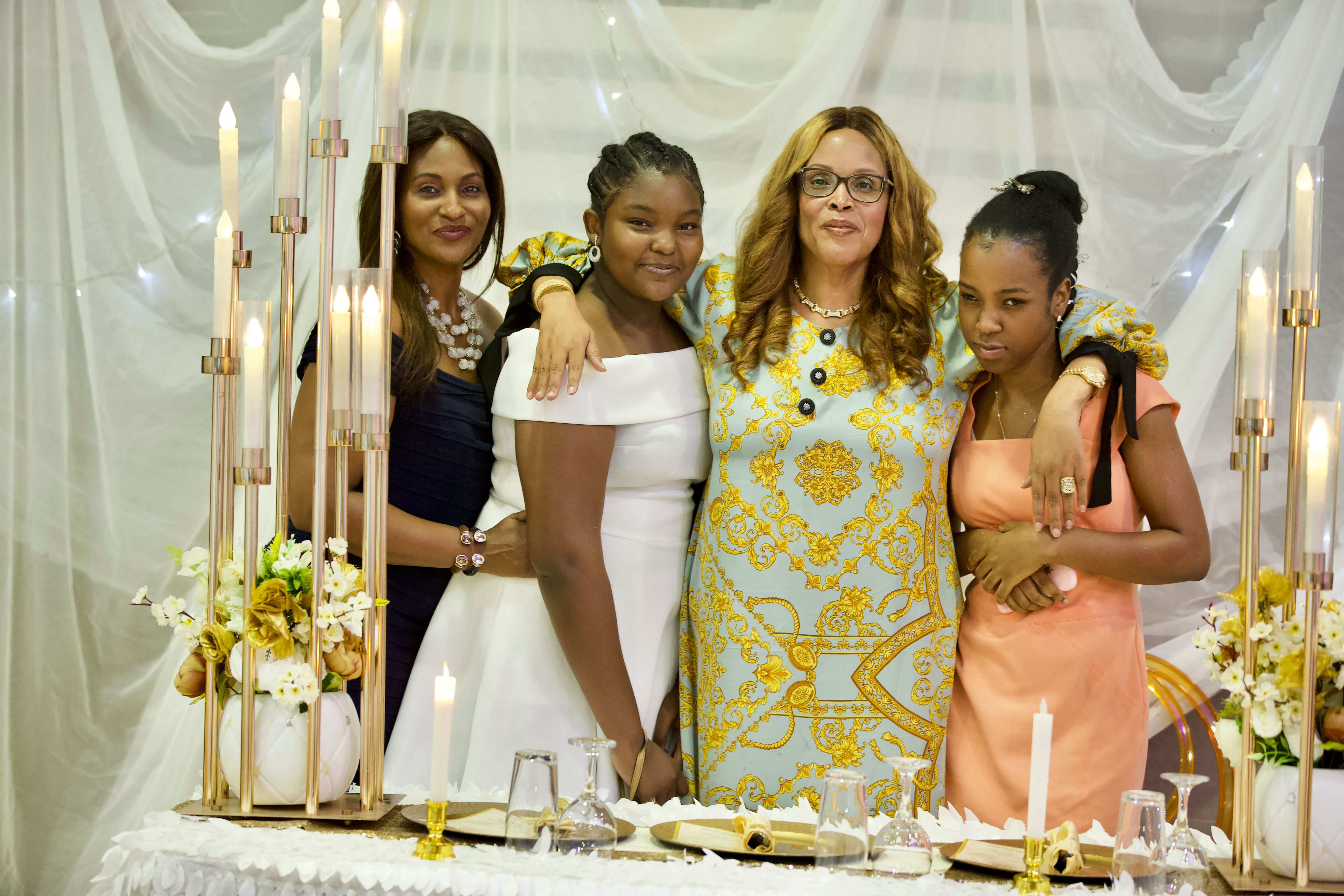 Four family members arm in arm at a candlelit celebration