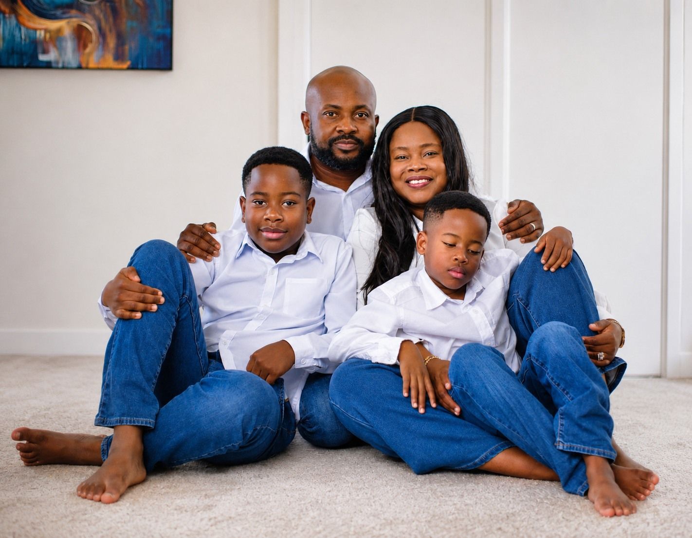 Family of four in white shirts and jeans, seated together on the floor
