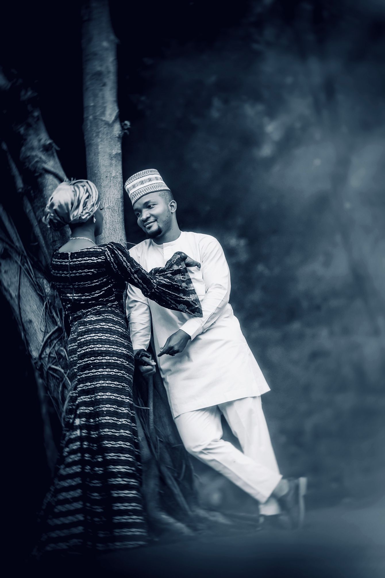 Bride and groom leaning together against a tree, black and white