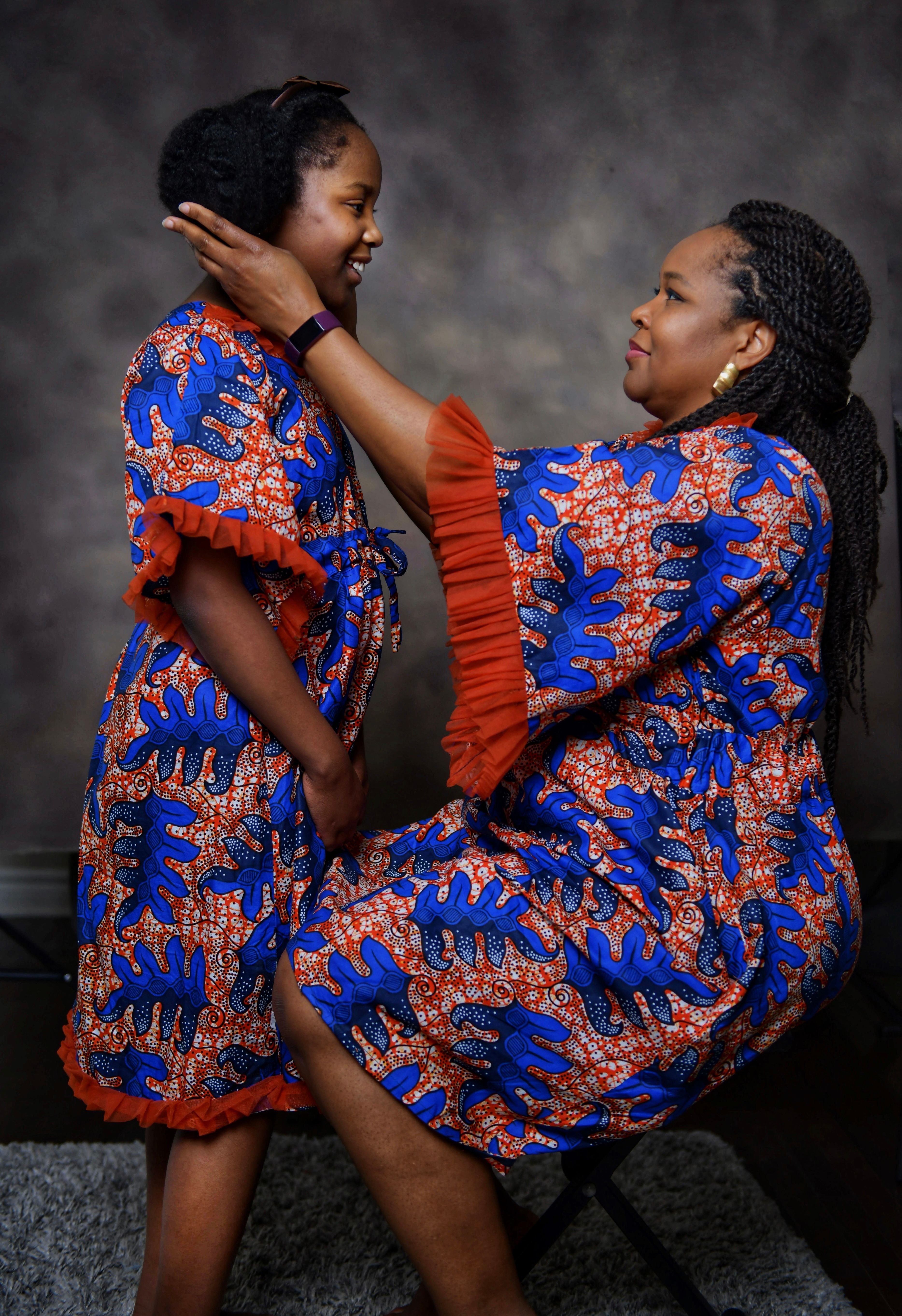 Mother and daughter in matching African print dresses, laughing together