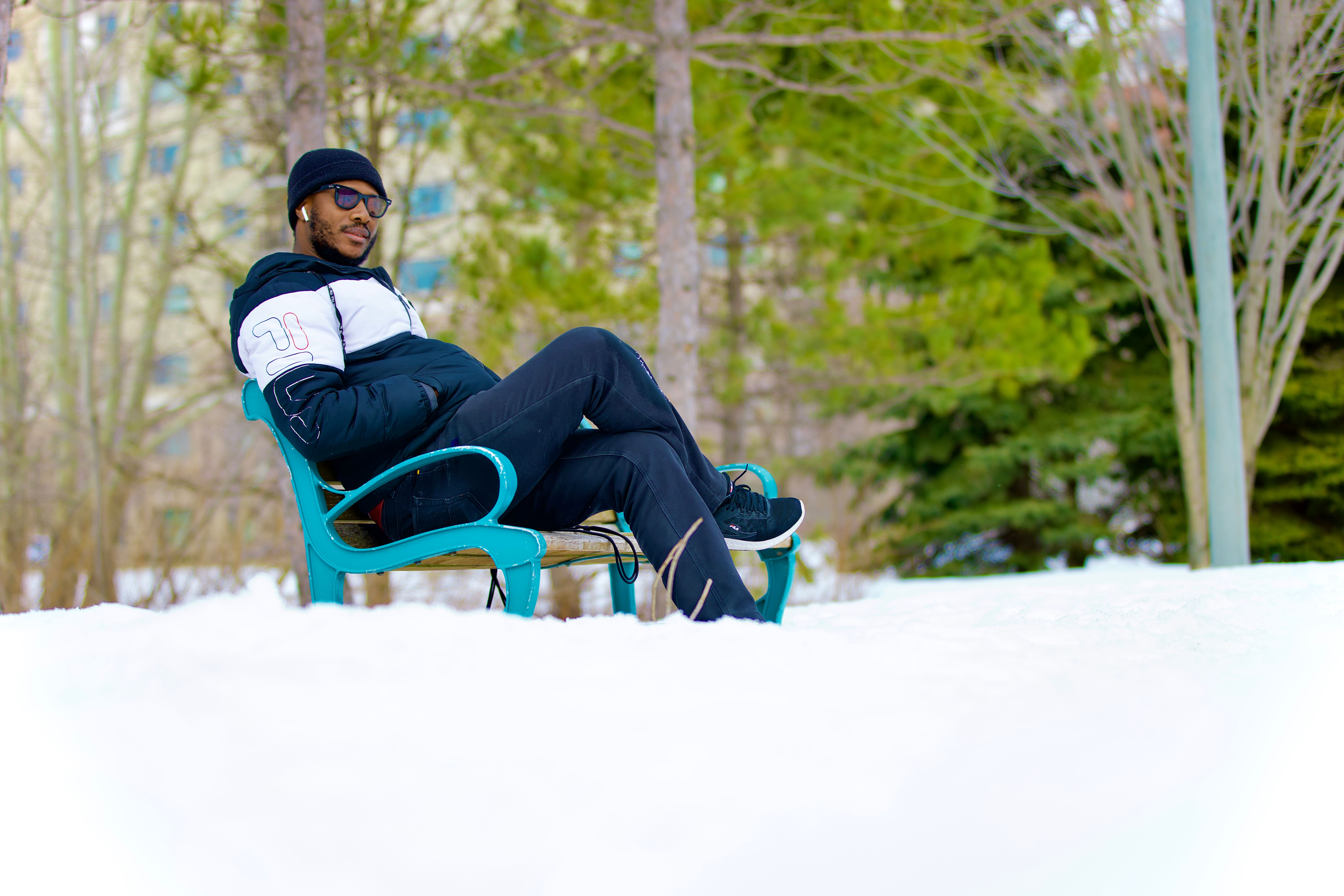 Man relaxing on a teal park bench in fresh snow