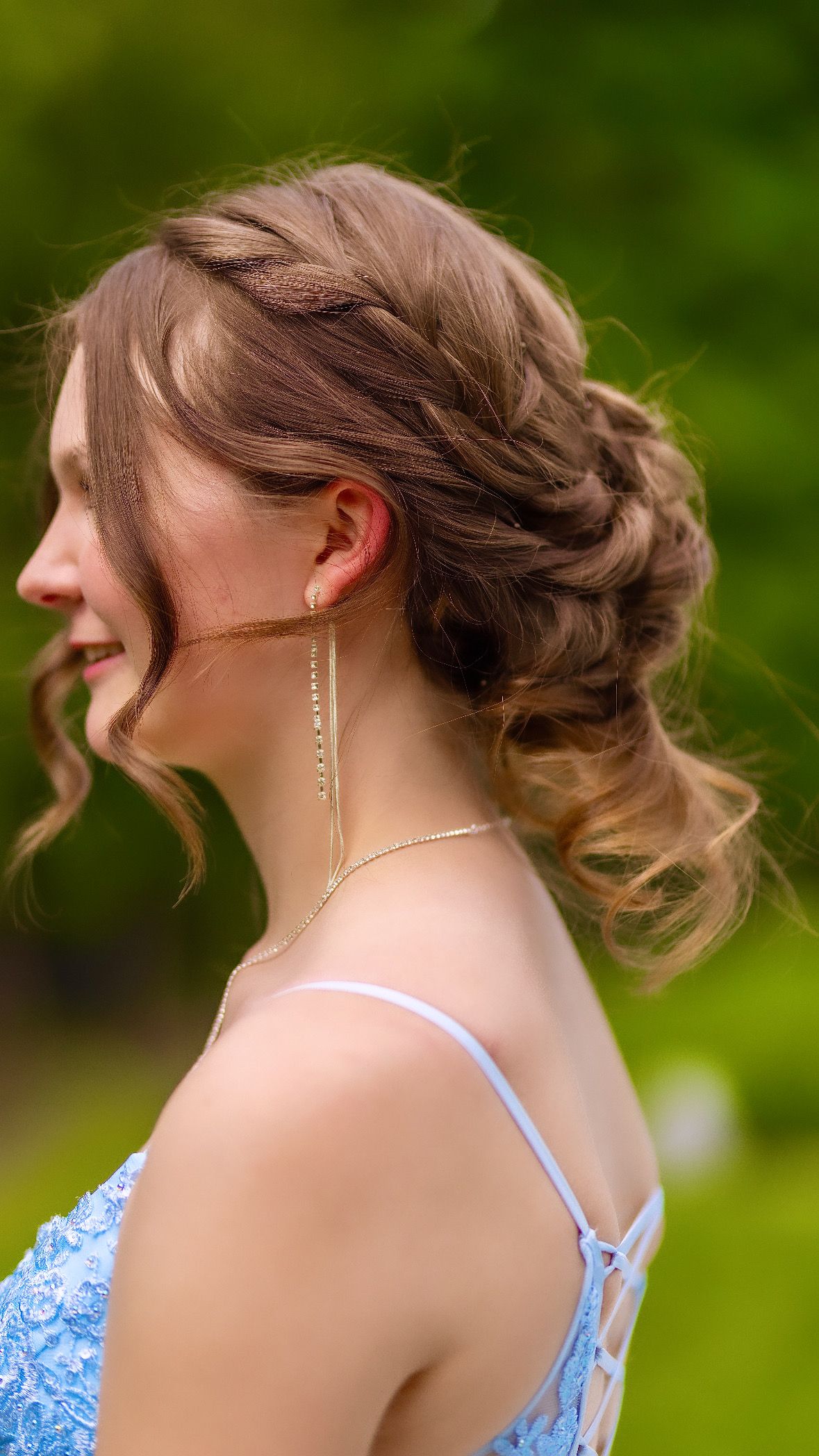 Detail of a braided updo and drop earrings, seen from behind