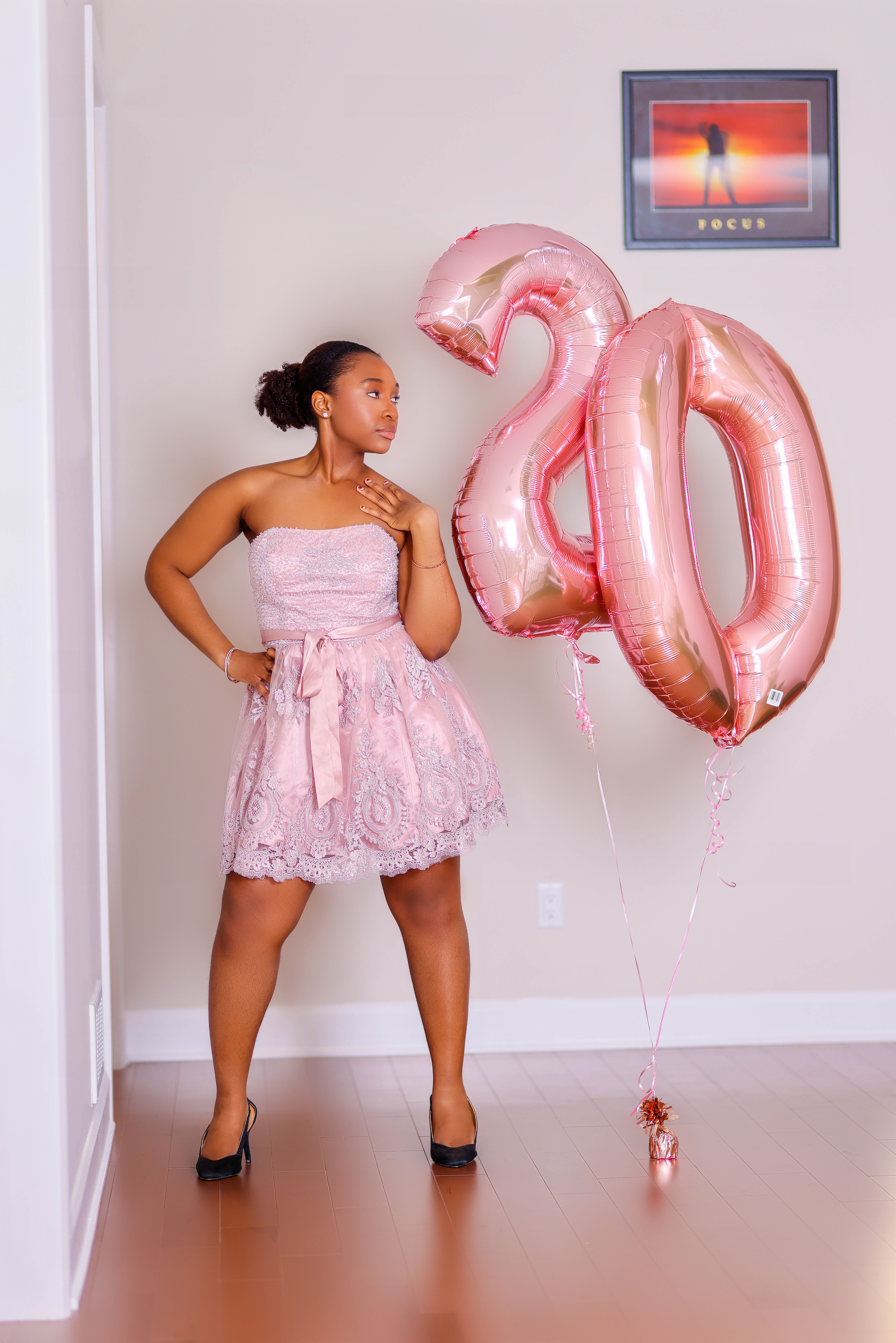 Milestone birthday portrait in a blush lace dress beside rose-gold balloons