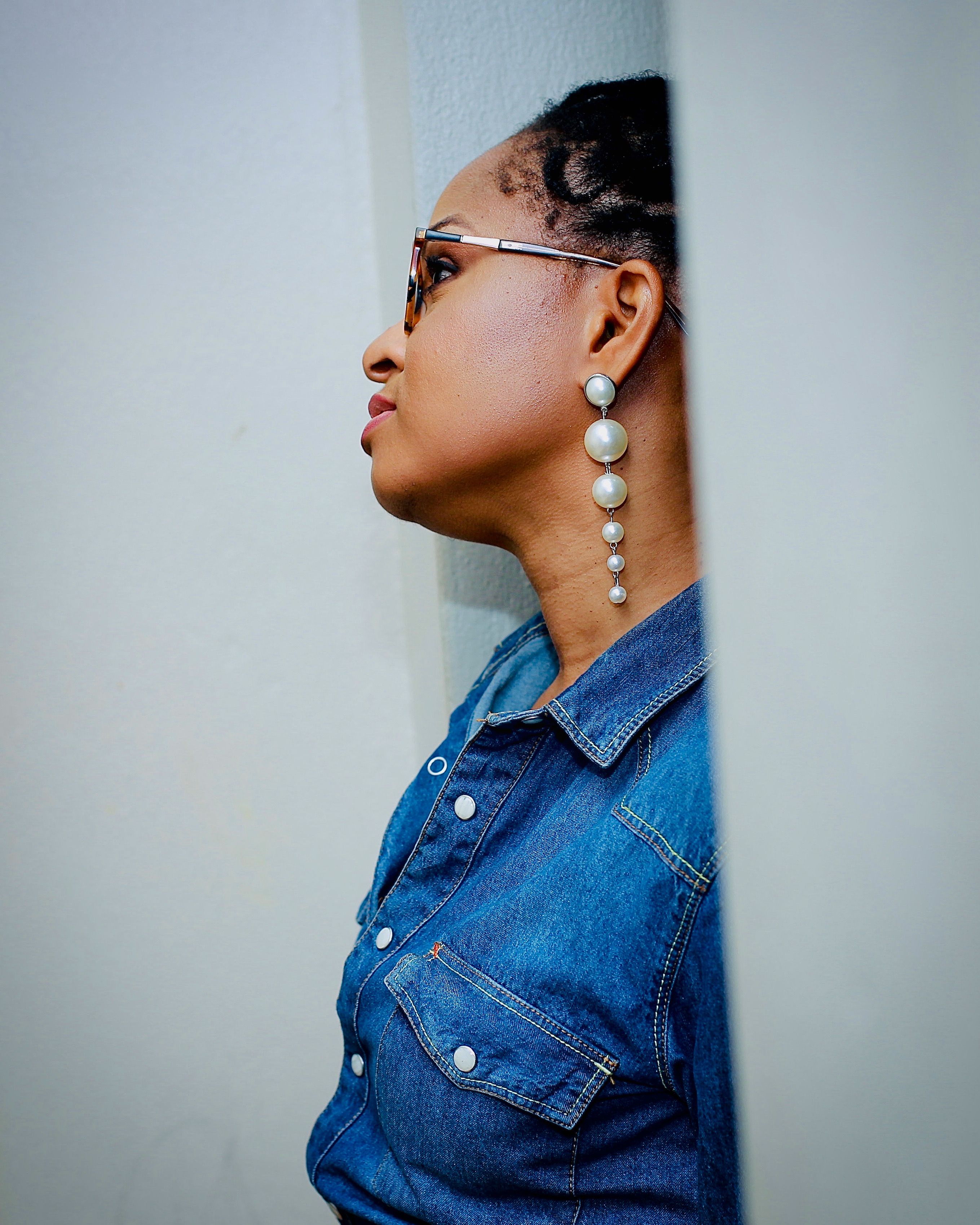 Side profile portrait with pearl drop earrings and a denim jacket