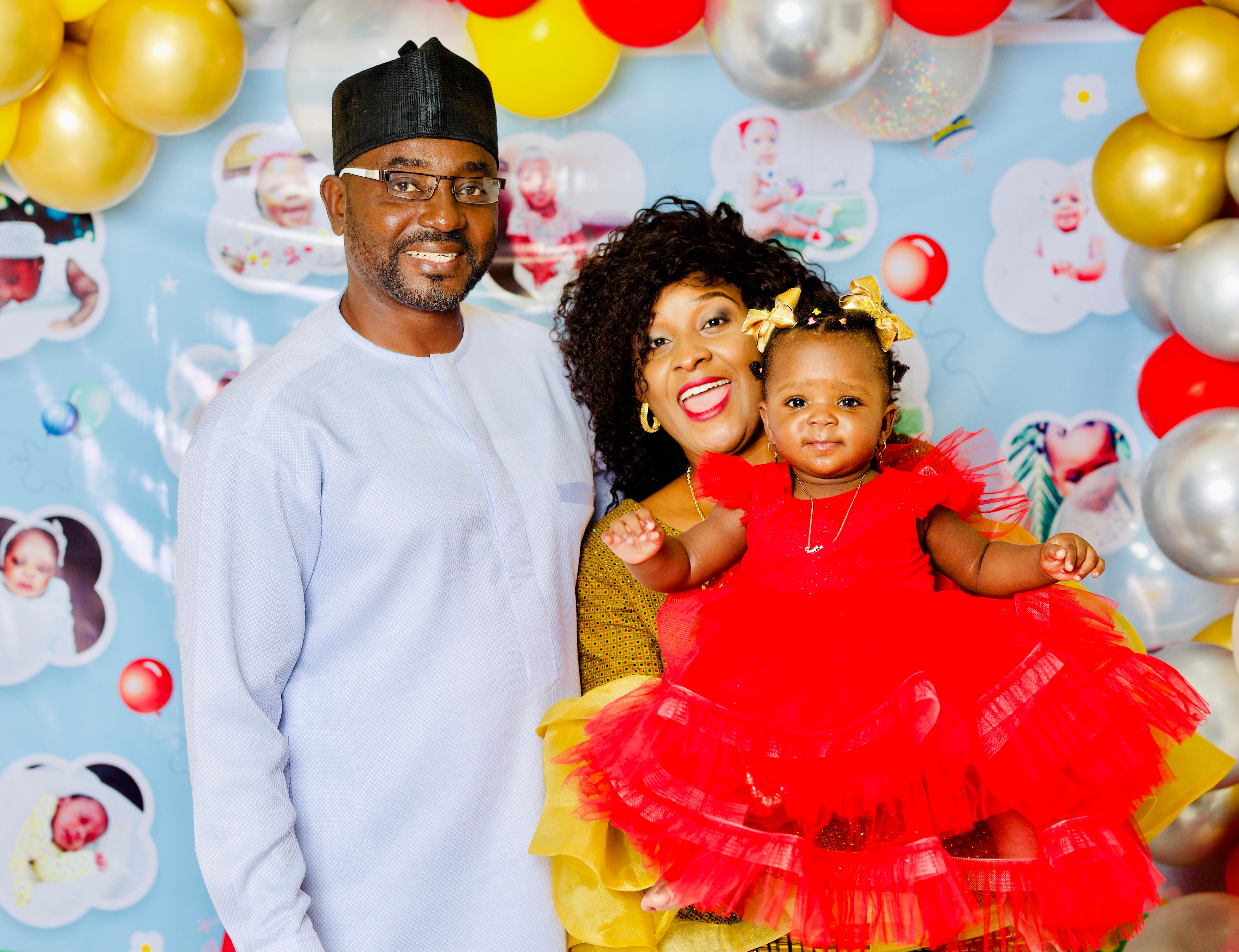 Parents holding their daughter in a red tulle dress at her birthday party