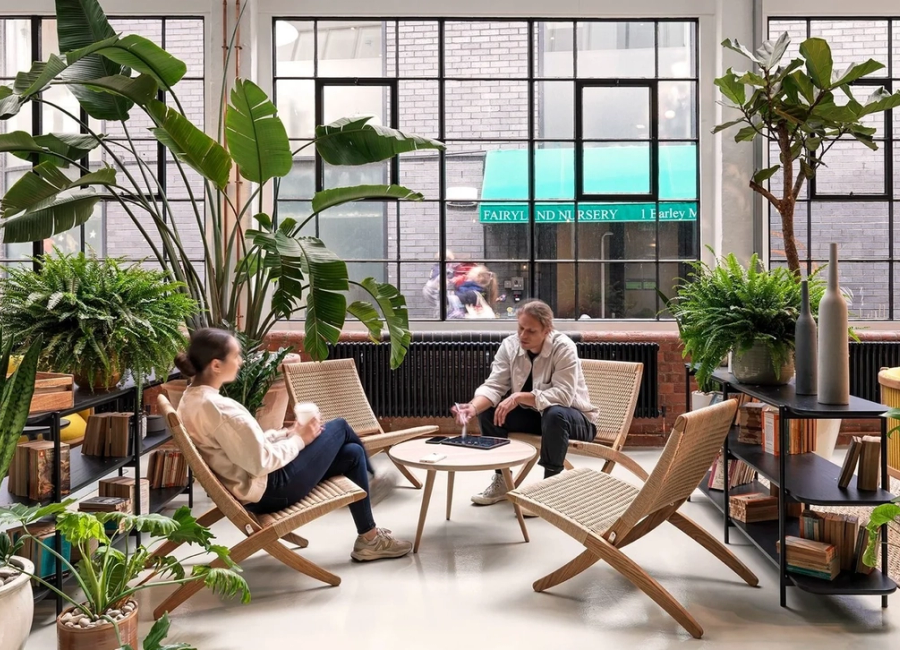A couple of people sat in some deck-chair-like chairs around a round table, enjoying drinks