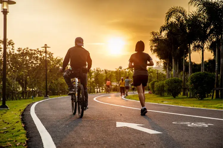 Team cycling and running on a park road at sunset