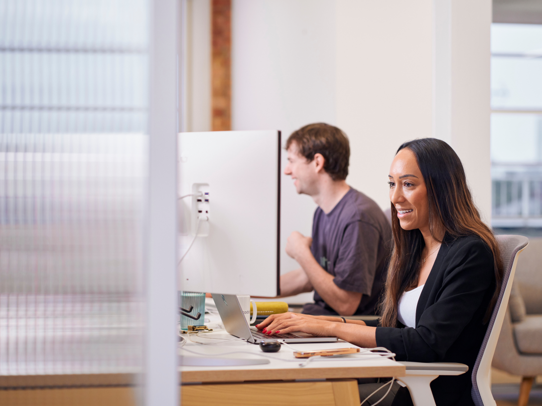 A woman is smiling as she types on the keyboard.