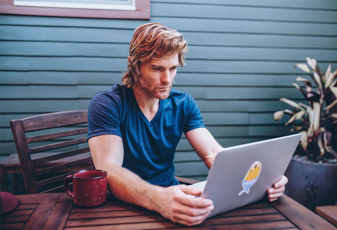 Person wearing t-shirt who is on their laptop