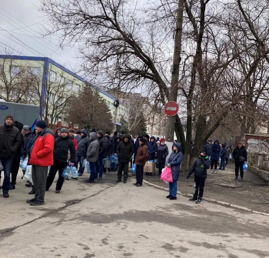 Ukrainians in winter clothing standing in a line for water