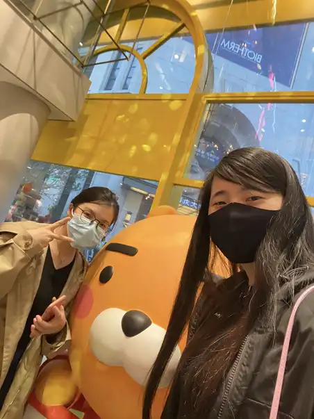 Two women posing with Kakao Talk's Ryan the Lion mascot