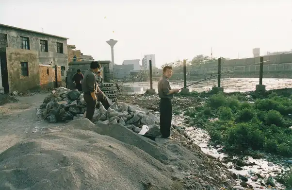 People standing atop rocks fishing in a river