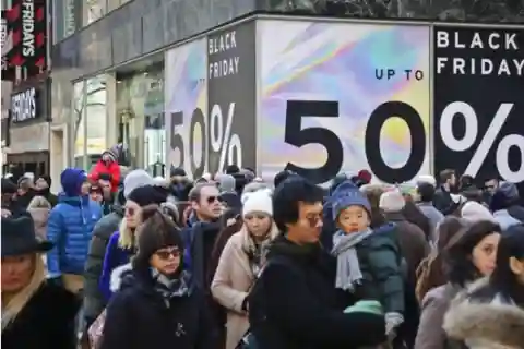 Crowd standing in front of a wall that displays a black friday ad.
