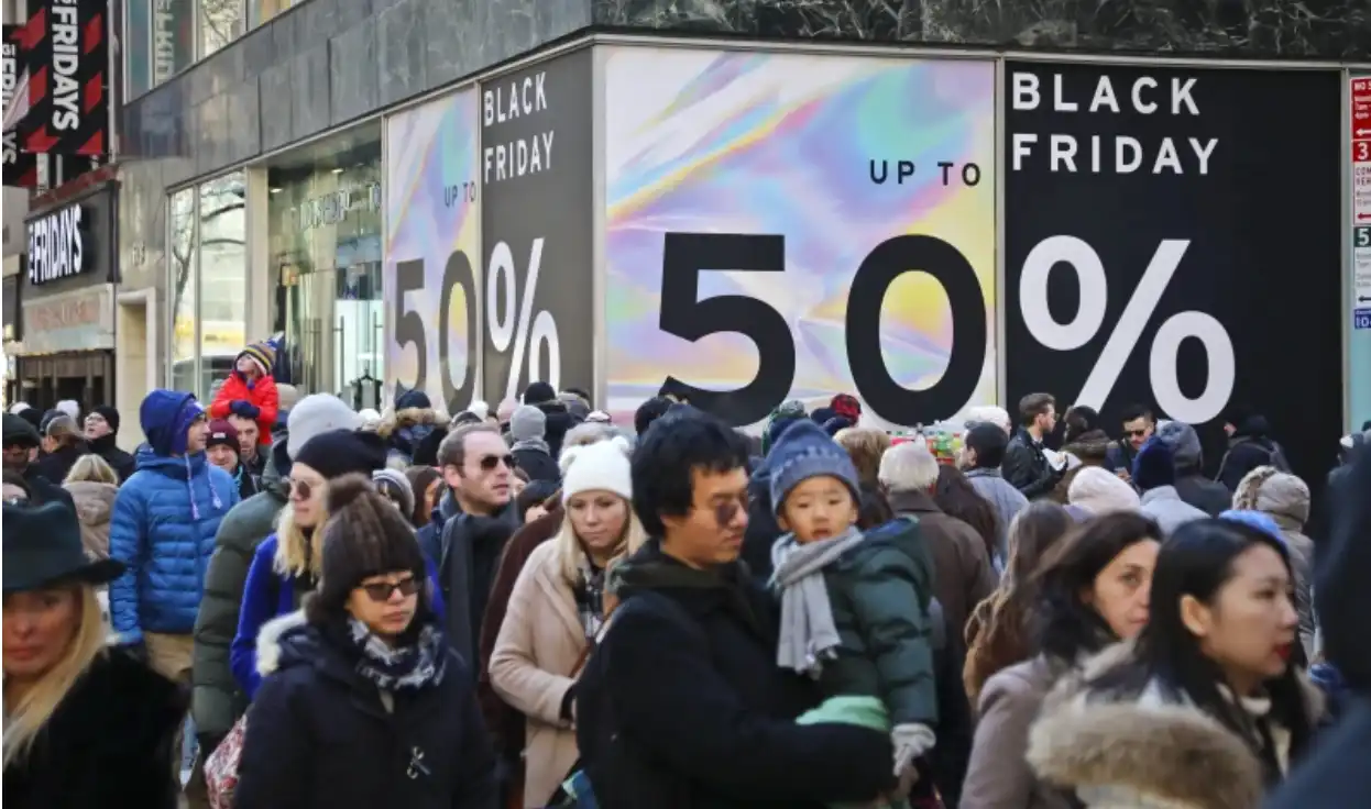 Crowd standing in front of a wall that displays a black friday ad.