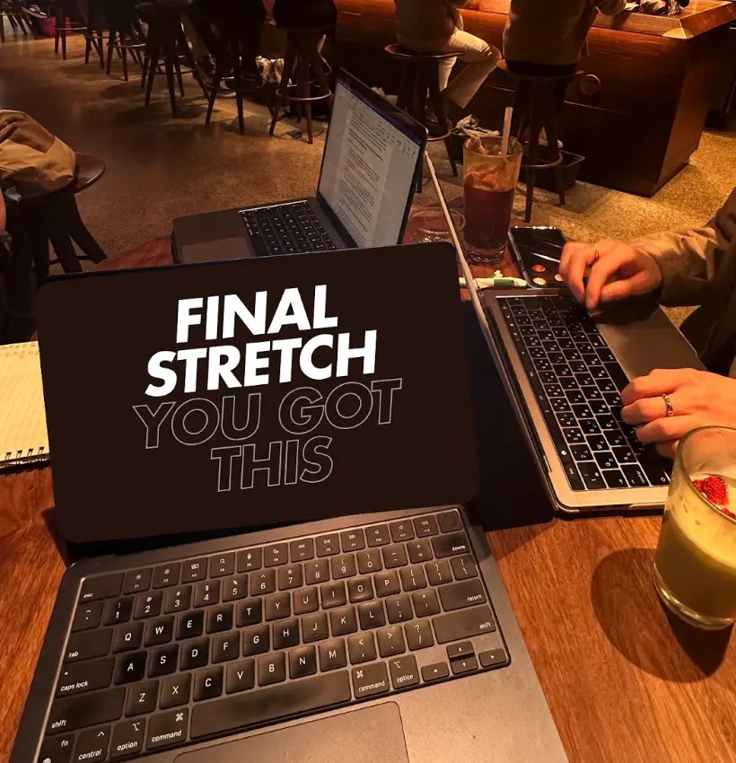 Picture of a computer displaying the words "Final Stretch You Got This" on a table in a cafe