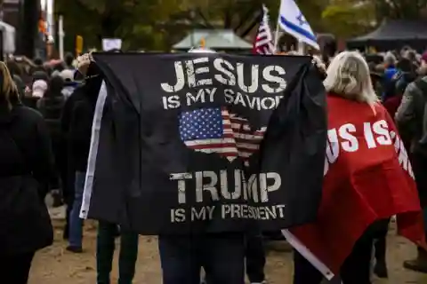 A black flag depicting the words 'jesus is my savior, Trump is my president'