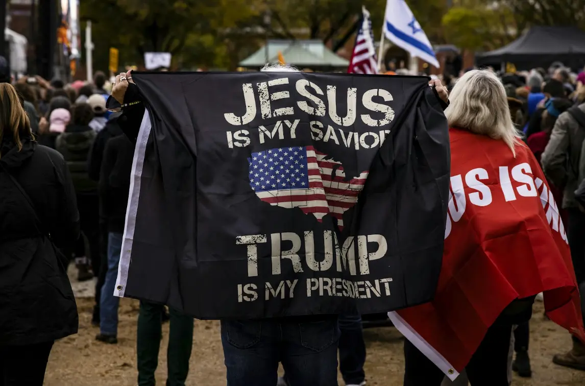 A black flag depicting the words 'jesus is my savior, Trump is my president'