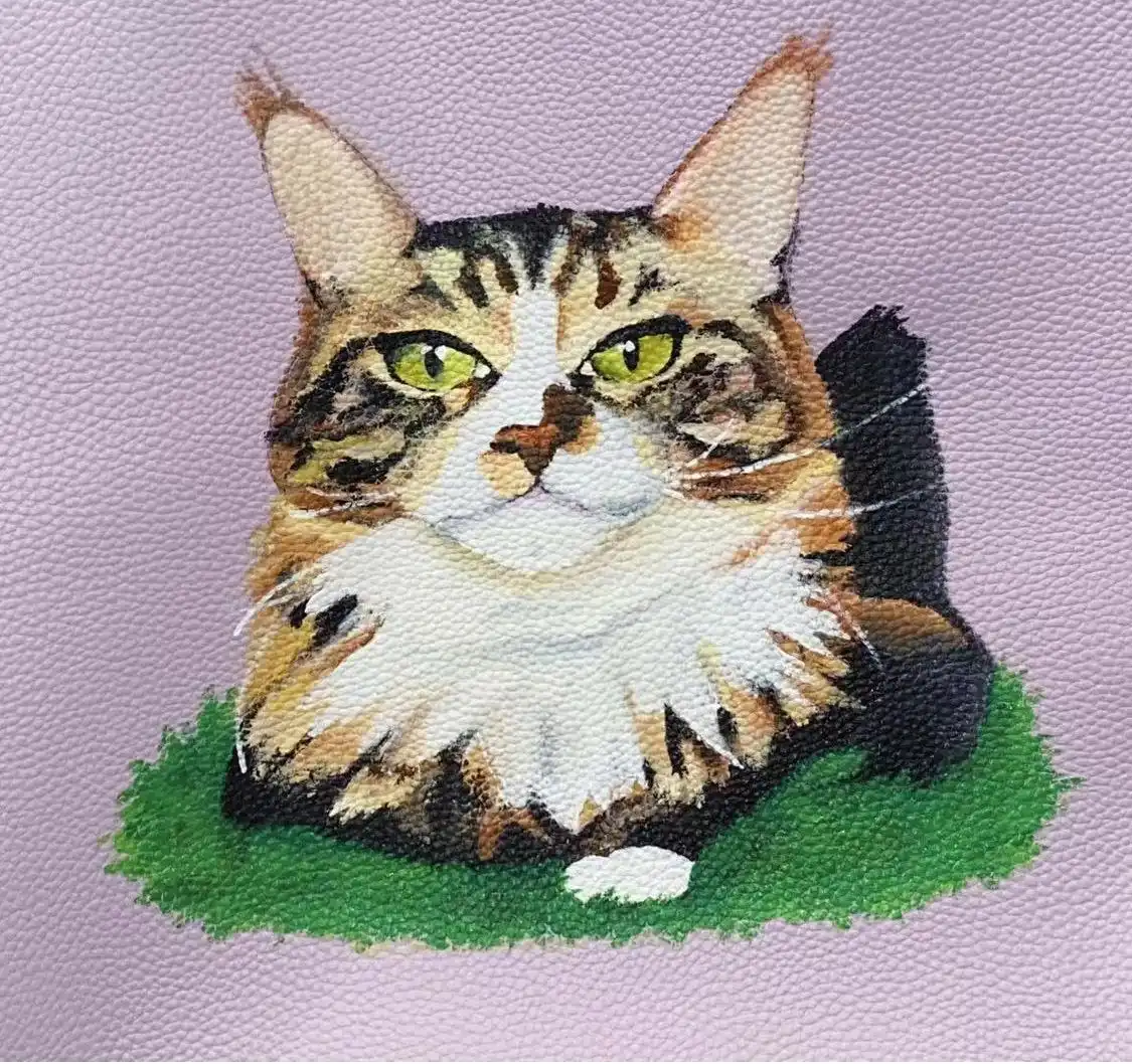 A calico cat painted onto purple leather