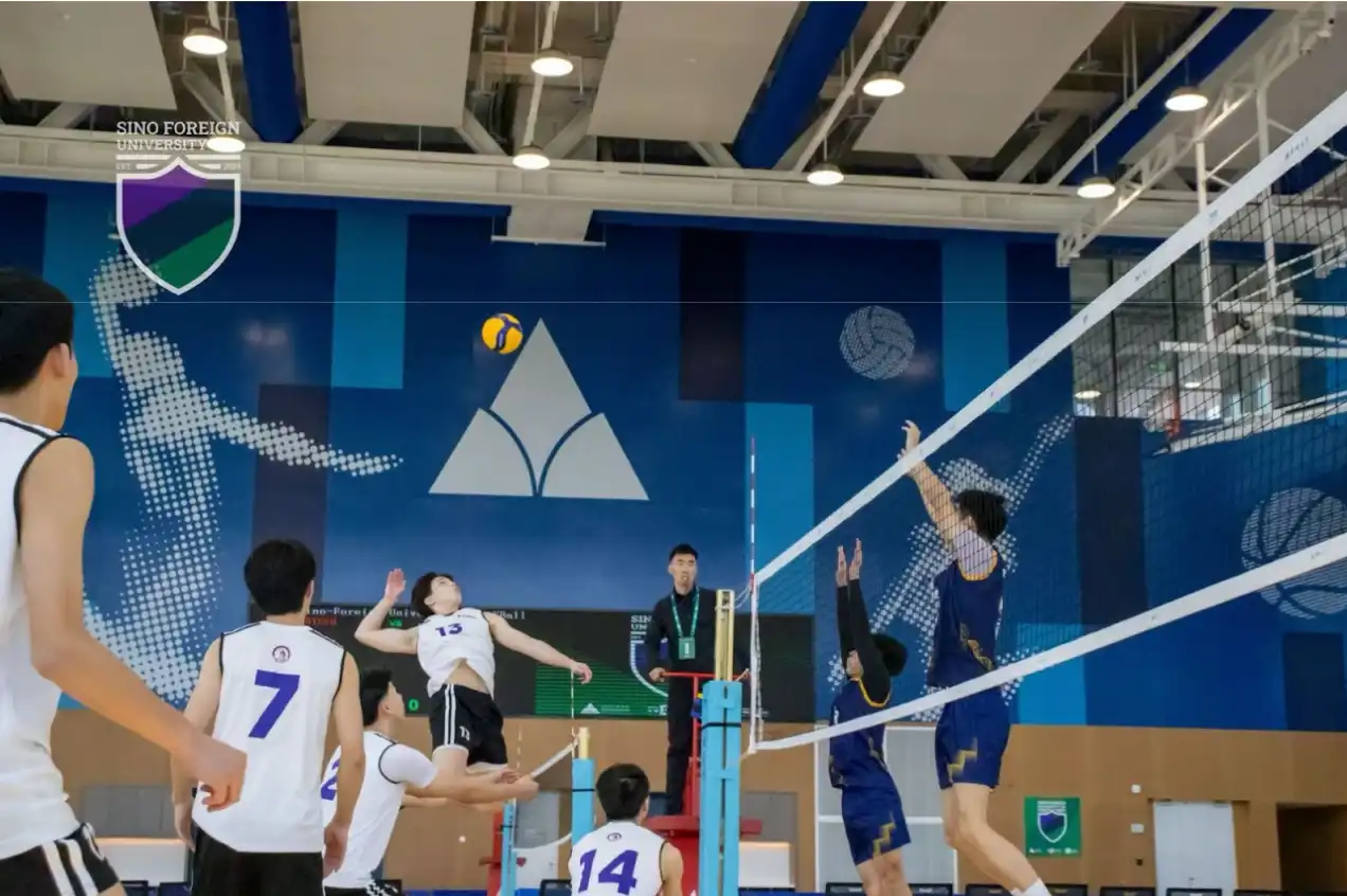 A man on NYU Shanghai volleyball team leaping for a spike