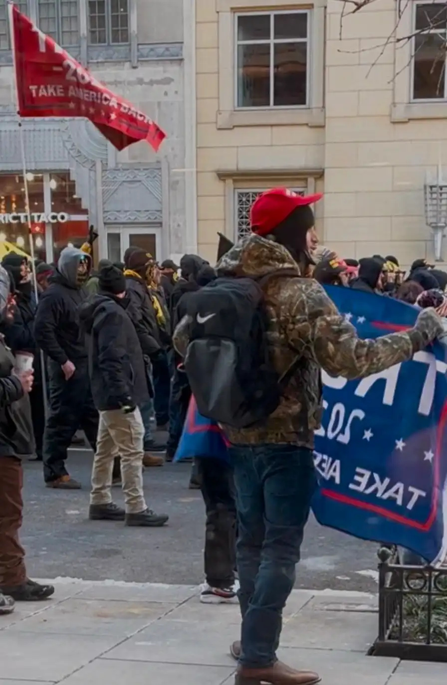 Man standing with a Trump flag.