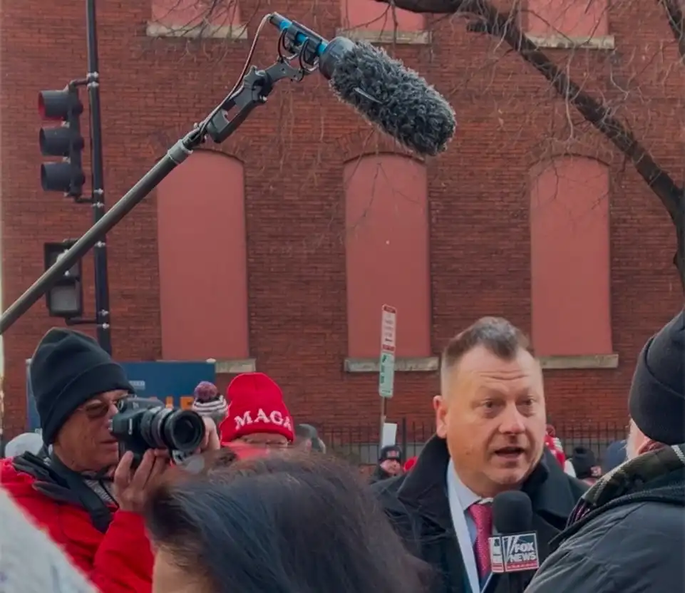 Imagine of a man reporting news to a camera.
