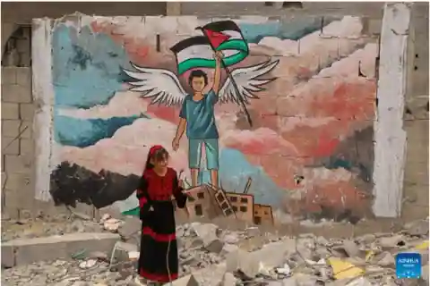 Little girl standing in front of a Palestinian mural.