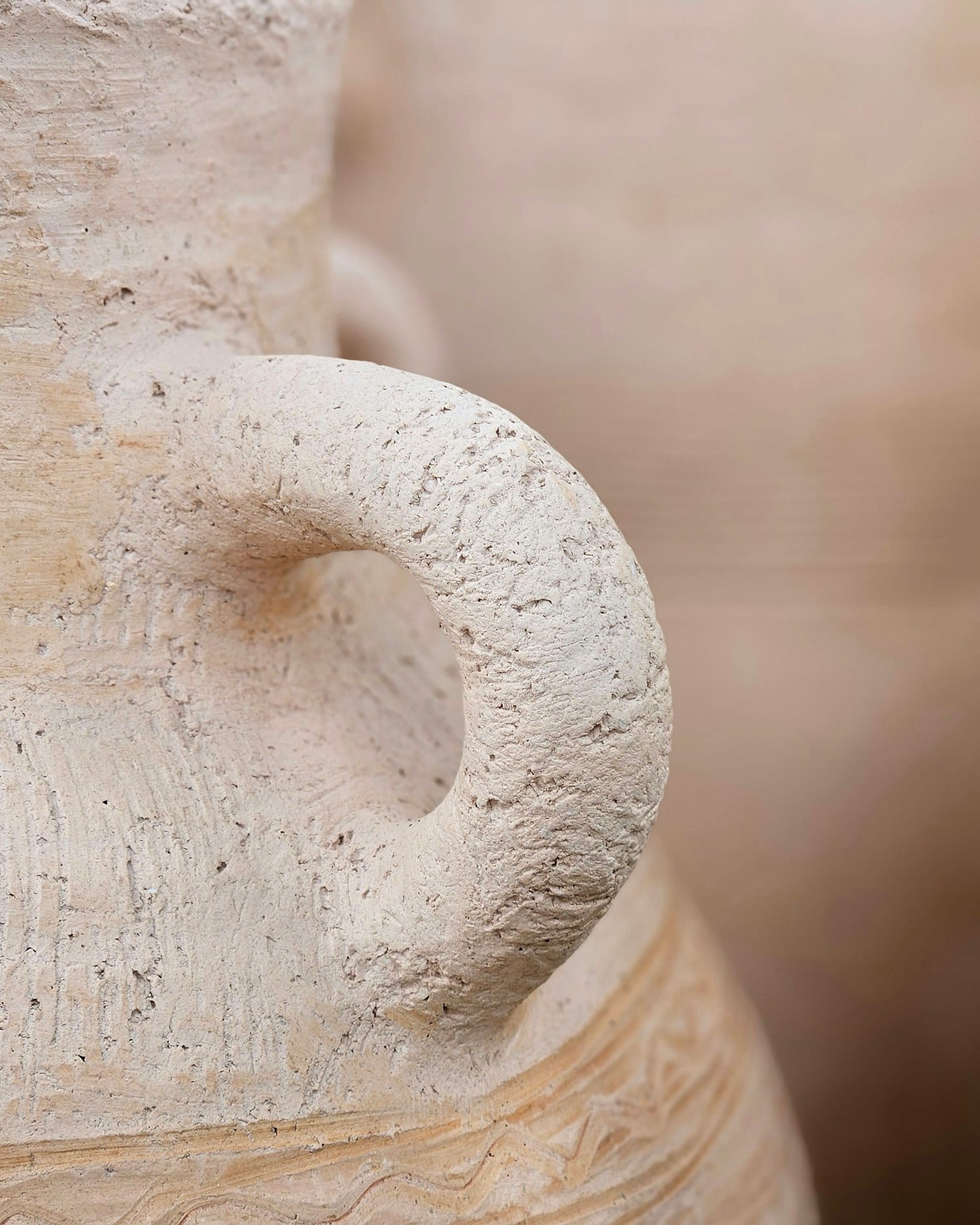 A chalky unglazed vessel photographed close, its surface left raw