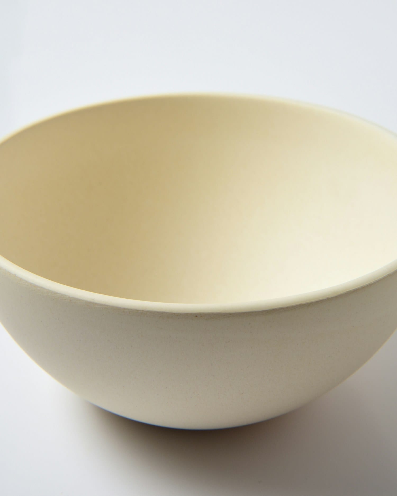 A deep cream serving bowl photographed against a plain white ground