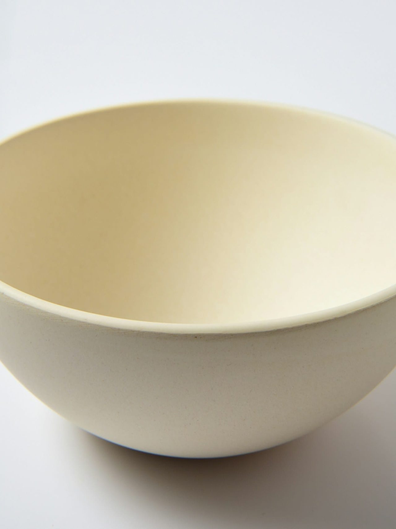A deep cream serving bowl photographed against a plain white ground