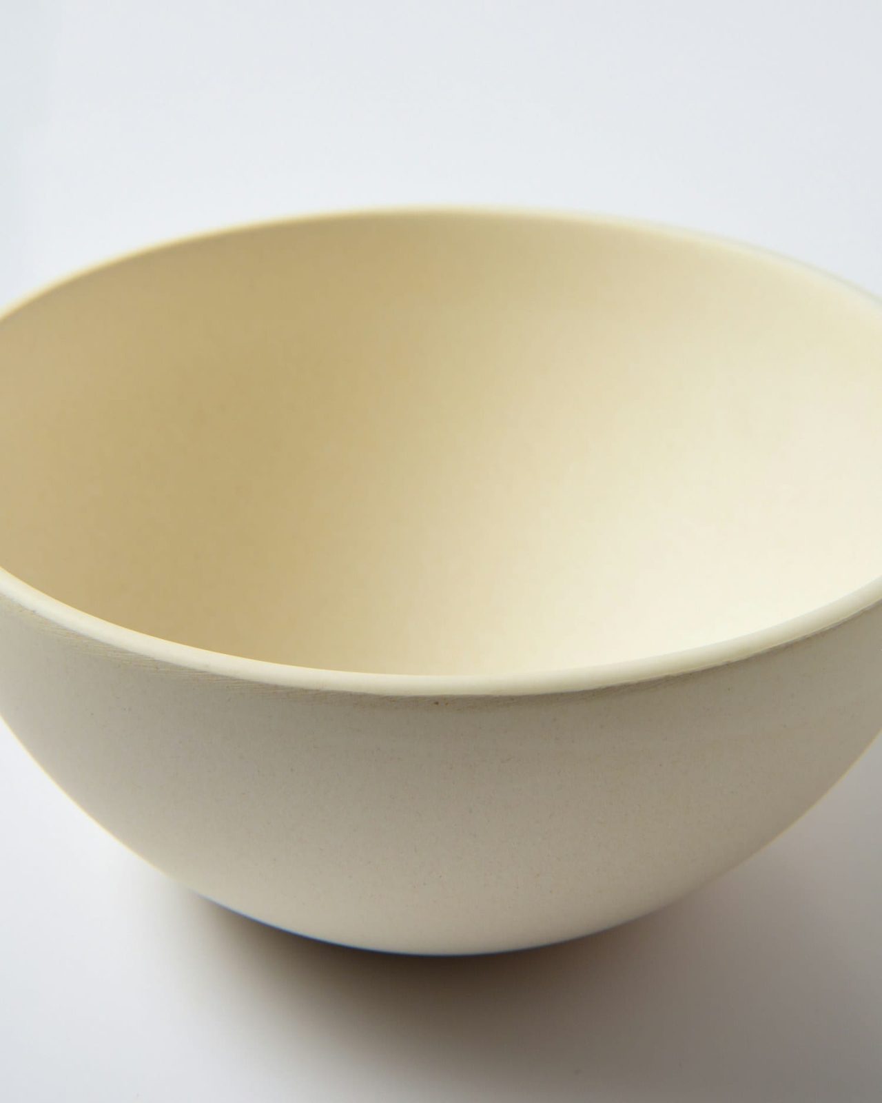 A deep cream serving bowl photographed against a plain white ground