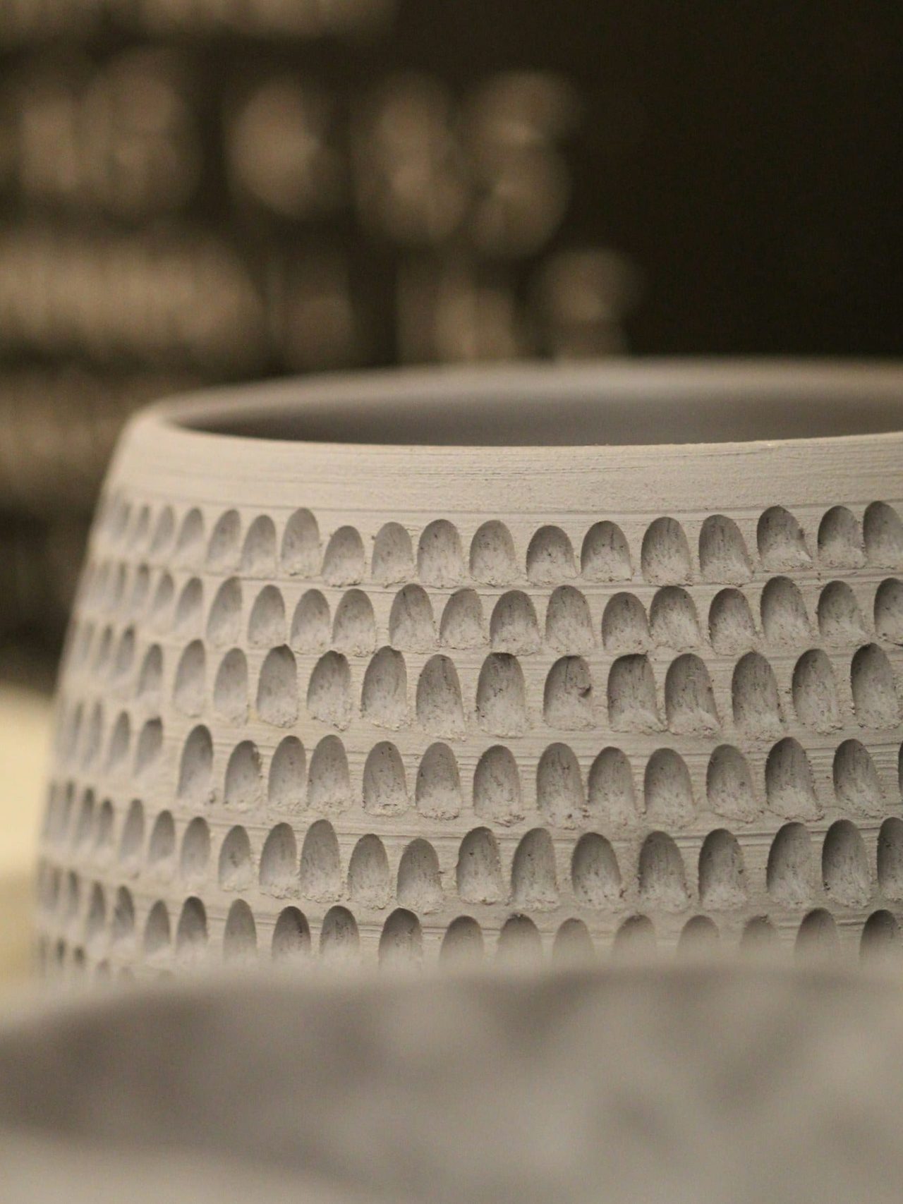 A tall vessel carved by hand with repeating vertical facets