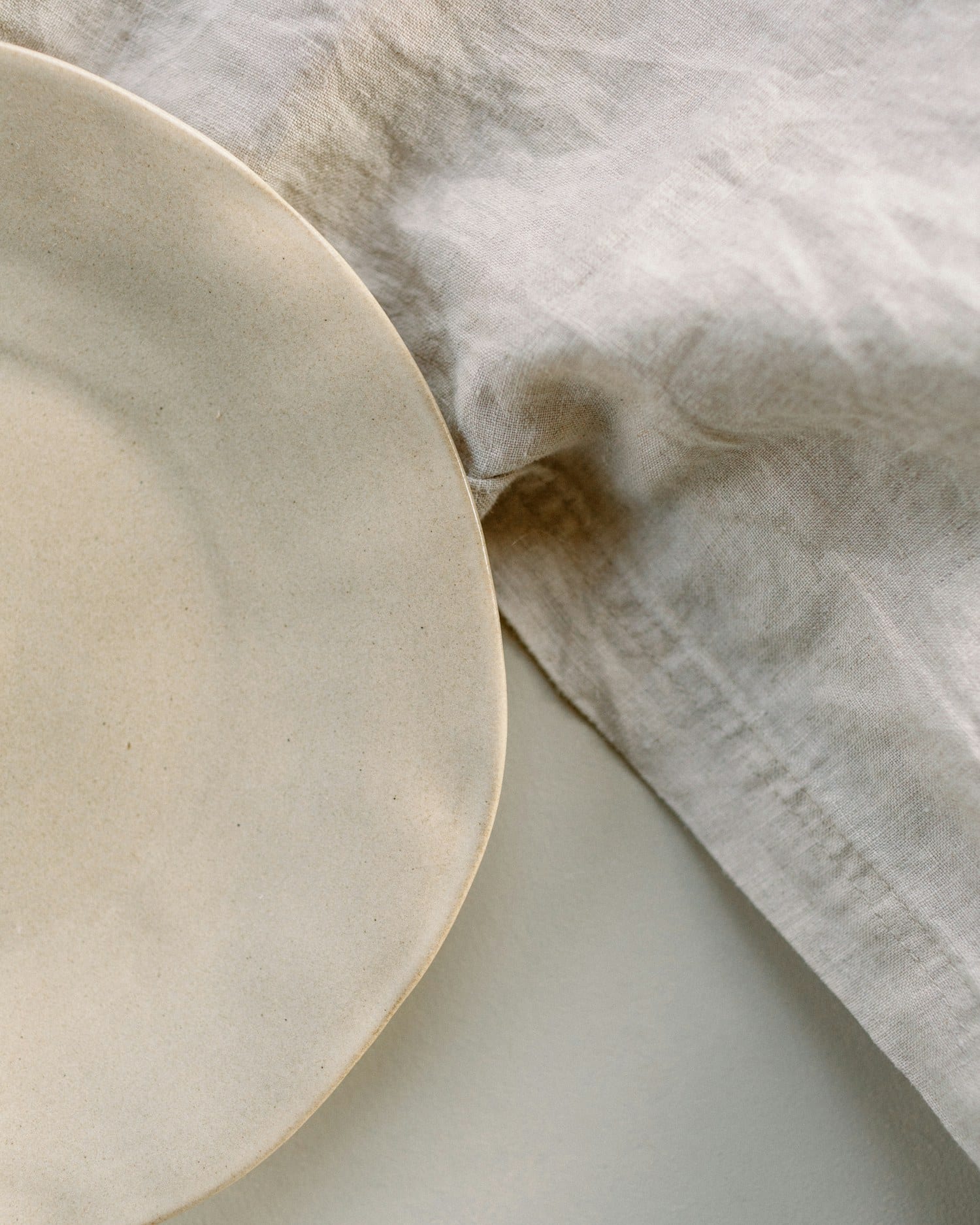 A large serving plate half-covered by a fold of natural linen