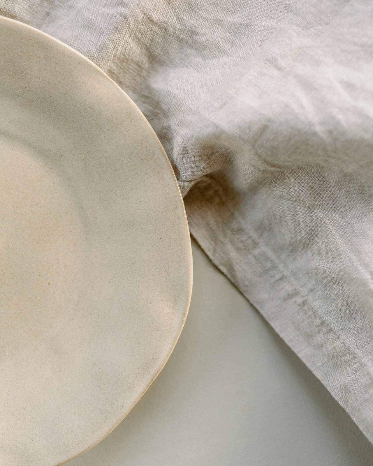 A large serving plate half-covered by a fold of natural linen