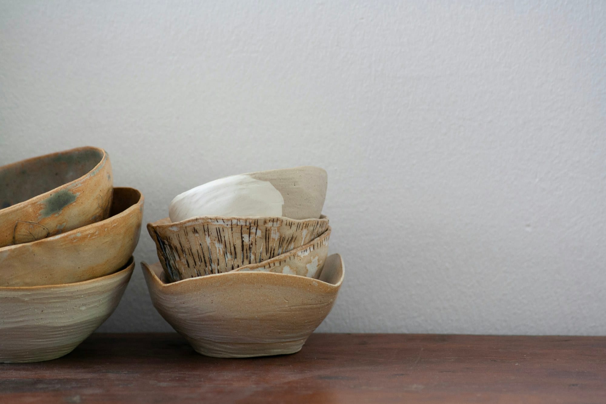 Hand-thrown bowls resting on a studio shelf, each finished in a different glaze