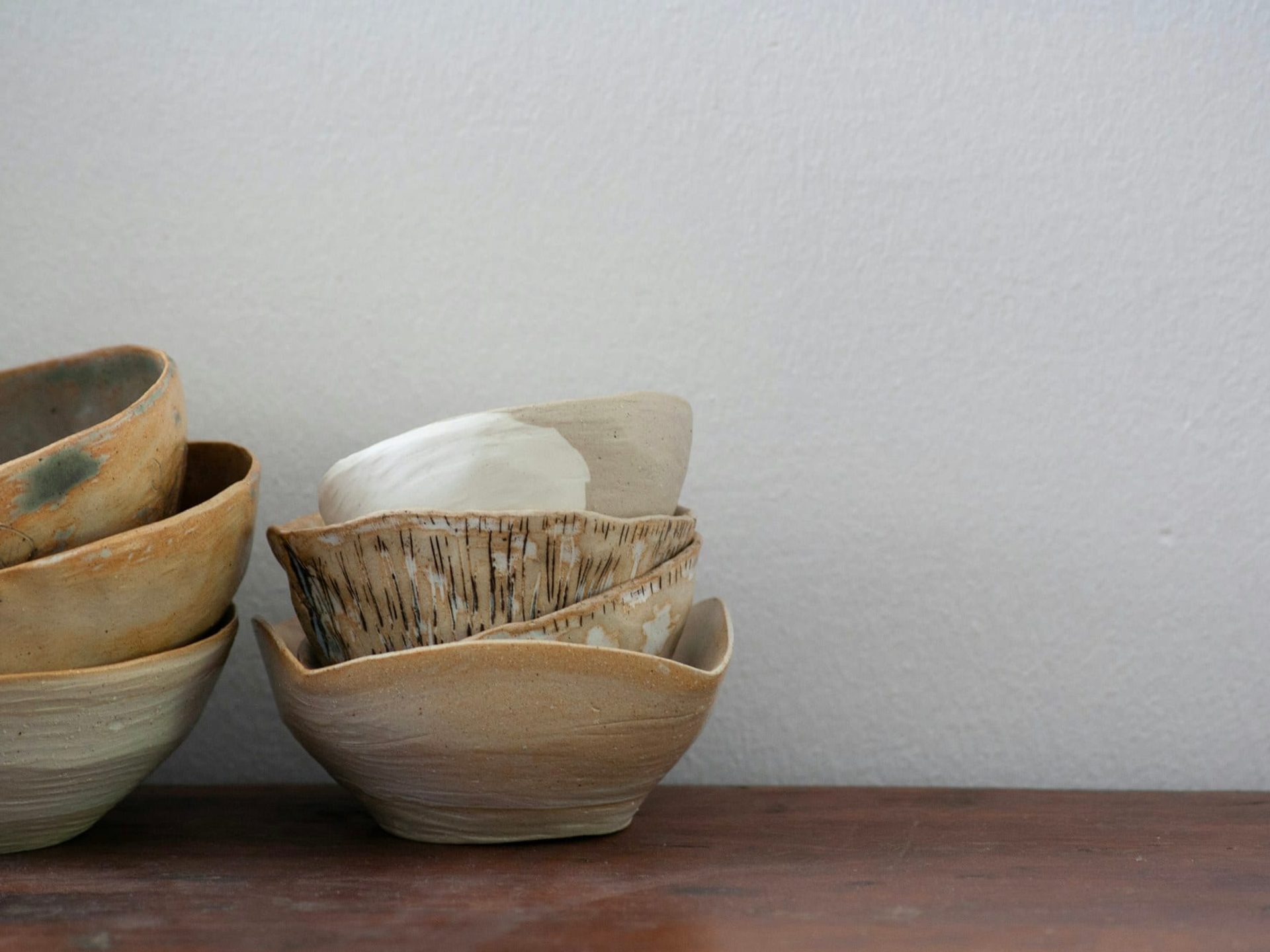 Hand-thrown bowls resting on a studio shelf, each finished in a different glaze