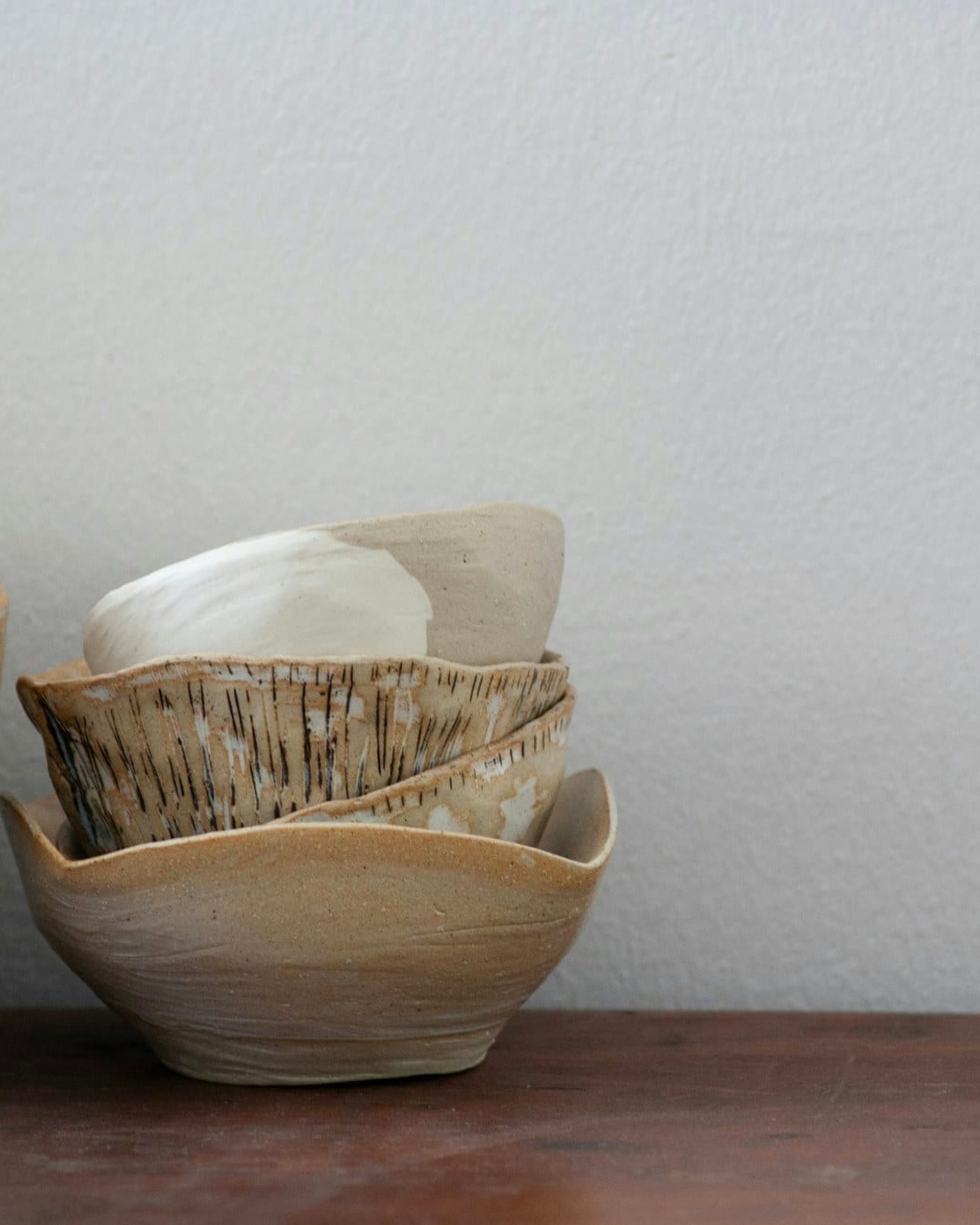 Hand-thrown bowls resting on a studio shelf, each finished in a different glaze
